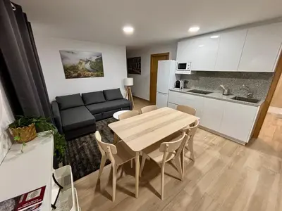a kitchen and a living room with a table and a couch at Apartamentos O Grilo in Doade