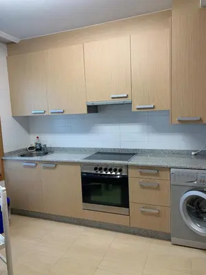 a kitchen with a stove and a washing machine at Sea, pool, and comfort in a duplex in Foz