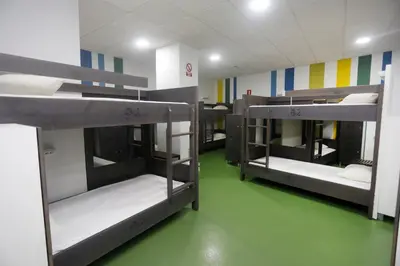 three bunk beds in a room with a green floor at Albergue Spa Cruceiro de Pedrouzo in O Pedrouzo