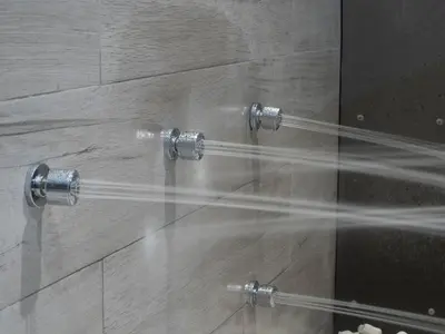 a shower with two shower heads and a glass wall at Albergue Spa Cruceiro de Pedrouzo in O Pedrouzo