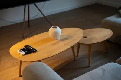 a table with a vase and two remote controls on it at APARTAMENTOS SARMIENTO - ÁTICO in Mondoñedo