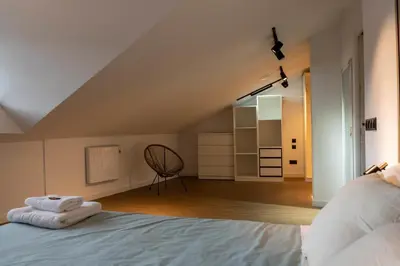 a bedroom with a bed and a chair in it at APARTAMENTOS SARMIENTO - ÁTICO in Mondoñedo