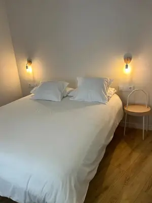 a large white bed with two pillows and a table at Pensión do Catro in Puebla de Trives