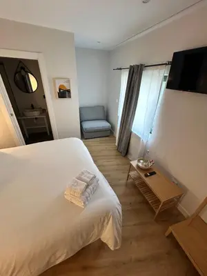 a bedroom with a bed and a tv and a chair at Pensión do Catro in Puebla de Trives