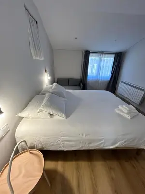 a large white bed in a room with a window at Pensión do Catro in Puebla de Trives