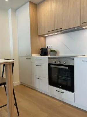 a kitchen with white cabinets and a black oven at Apartamento R14 en Miño con 2 dormitorios, salón-cocina, 1 baño y zona de lavandería, situado cerca de las playas in Miño