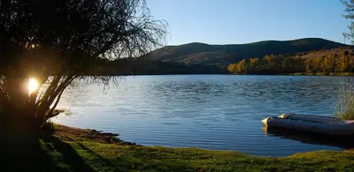 a boat sitting on a lake with the sun setting at Casa Divina in Lago de Carucedo