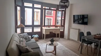 a living room with a couch and a table and a desk at Apartamento Galería Cine Colón in Ribadeo
