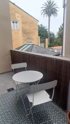 a table and chairs on a balcony with a palm tree at Apartamento Galería Cine Colón in Ribadeo