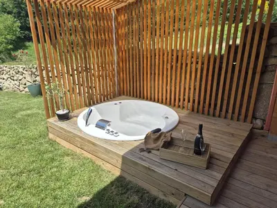 a hot tub with a bottle of wine on a wooden deck at Palleira da Aira in Entrambosríos