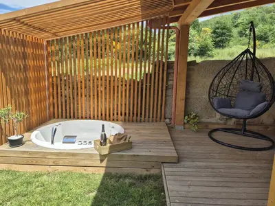 a hot tub sitting on a wooden deck with a chair at Palleira da Aira in Entrambosríos