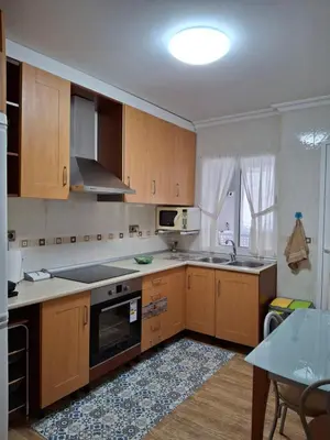 a kitchen with wooden cabinets and a sink and a table at El hogar de 2 y 4 patas in Silleda