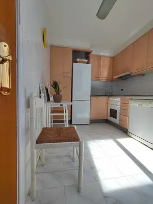 a kitchen with a table and a white refrigerator at Apartamento centro de Sada in Sada