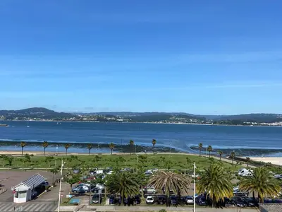 a view of a beach with palm trees and a parking lot at Apartamento centro de Sada in Sada