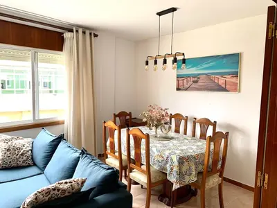 a dining room with a table and a couch at Apartamento Playa de Foz in Foz