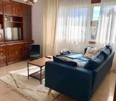 a living room with a blue couch and a table at Apartamento Playa de Foz in Foz