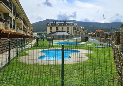 a fence in front of a building with two pools at Spa Costa Reinante in San Miguel de Reinante