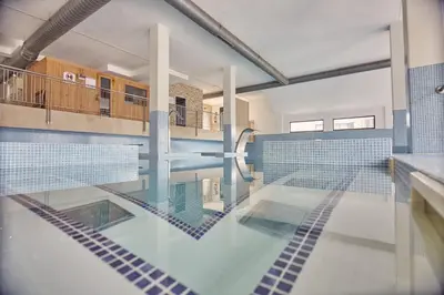 an indoor swimming pool with blue tiles on the floor at Spa Costa Reinante in San Miguel de Reinante