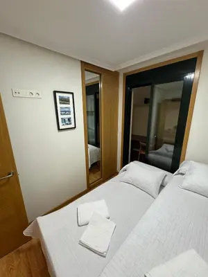a bedroom with a white bed and a mirror at Apartamento Rammari Spa in San Miguel de Reinante