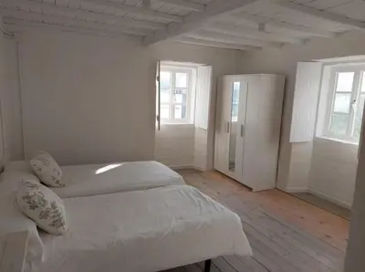 a white bedroom with two beds and two windows at Casa Castro in Lamas