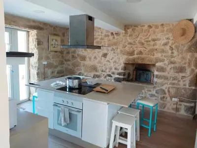 a kitchen with a stove and a stone wall at Casa Castro in Lamas