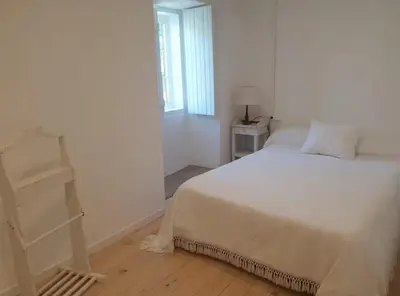 a white bedroom with a bed and a window at Casa Castro in Lamas