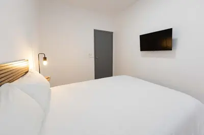 a white bedroom with a bed and a flat screen tv at Habitación en Apartamento Teo in Santiago de Compostela