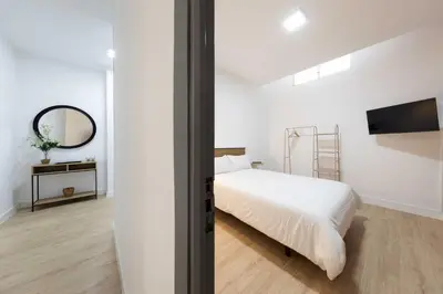 a white bedroom with a bed and a mirror at Habitación en Apartamento Teo in Santiago de Compostela