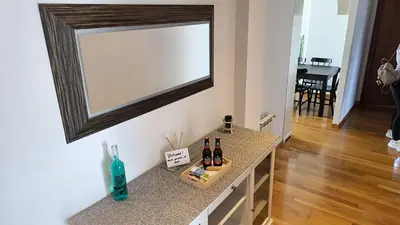 a mirror hanging on a wall with bottles on a counter at A&M Real Estate in Milladoiro
