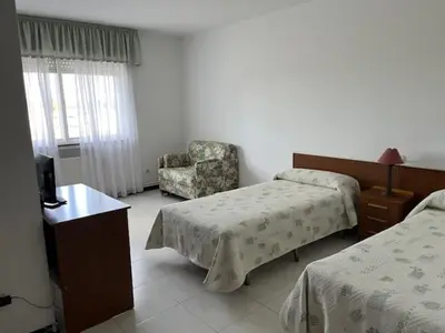 a hotel room with two beds and a chair at Hostal Delfino in Bardaos