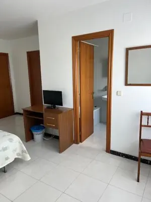 a room with a desk with a computer and a room with a bed at Hostal Delfino in Bardaos