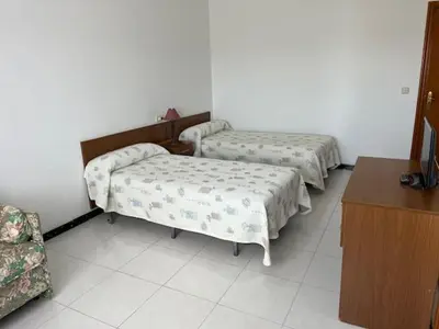 a room with two beds and a table and a desk at Hostal Delfino in Bardaos