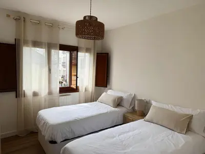 a bedroom with two beds and a window at Las Cuatro Calles in Ribadeo