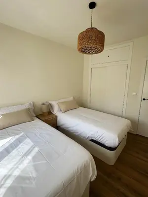 a bedroom with two beds and a chandelier at Las Cuatro Calles in Ribadeo