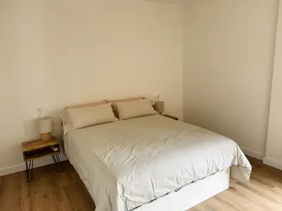 a bedroom with a white bed with a night stand at Las Cuatro Calles in Ribadeo