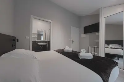 a white bedroom with a large bed and a bathroom at Kumano Kodo by Como en Casa in Santiago de Compostela
