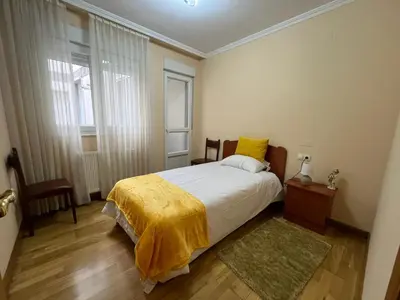 a bedroom with a bed with a yellow blanket on it at Apartamento Los Gallegos in Foz