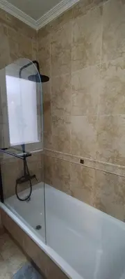 a bath tub with a glass shower stall in a bathroom at Apartamento Los Gallegos in Foz