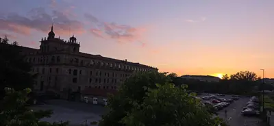 a sunset over a large building with a parking lot at Amma Ribeira Sacra in Monforte de Lemos