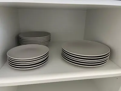 three plates on a shelf in a white cabinet at Vistas del Parque in Santiago de Compostela