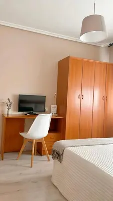 a bedroom with a white chair and a tv at Casa Pazos, Pedrafita do Cebreiro in Piedrafita