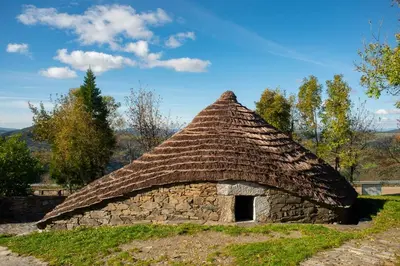 a stone building with a roof on a field at Casa Pazos, Pedrafita do Cebreiro in Piedrafita