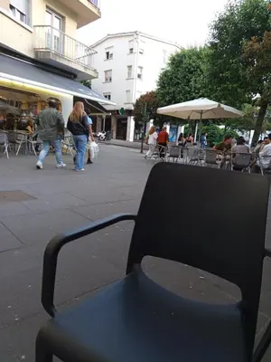 a bench sitting on a city street with people walking at Habitación de lujo in Santiago de Compostela