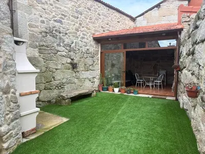 a patio with green grass next to a stone building at A casita das Pegas