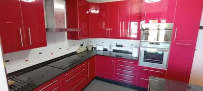 a red kitchen with white appliances and red cabinets at EnSAN CIPRIAN Con Vistas Al Mar in Cervo