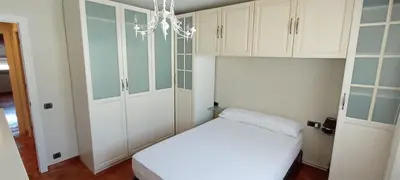 a bedroom with a bed and white cabinets and a chandelier at EnSAN CIPRIAN Con Vistas Al Mar in Cervo