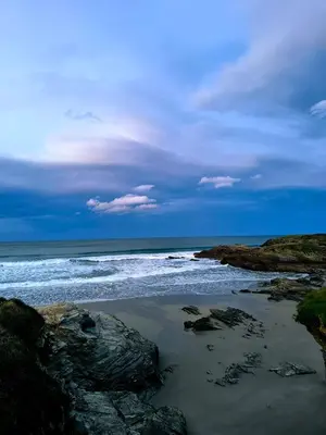 a beach with rocks and the ocean on a cloudy day at Cabaña de madera Mar y Madera, playa de las catedrales in Barreiros