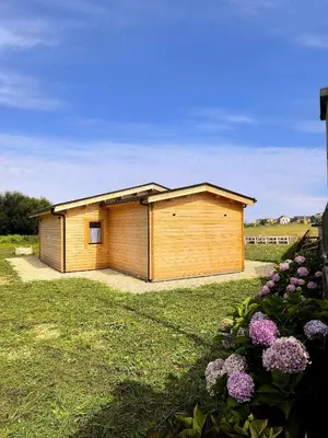 a small wooden building in a yard with flowers at Cabaña de madera Mar y Madera, playa de las catedrales in Barreiros