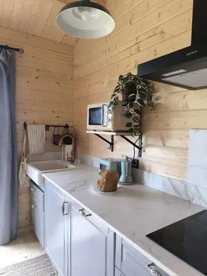 a kitchen with white counters and wooden walls at Cabaña de madera Mar y Madera, playa de las catedrales in Barreiros