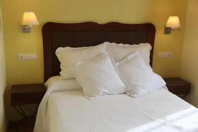 a bed with white pillows on it with two night stands at Casa De Aldea La Galea in Vegadeo